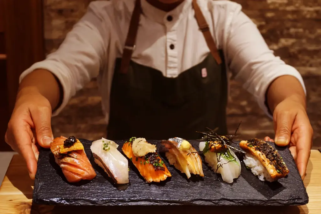 A chef presenting a curated platter of premium omakase sushi, showcasing the intimate culinary art where the chef personally selects seasonal ingredients to ensure harmony and freshness in every bite.
