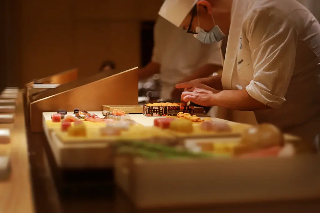 A chef carefully preparing intimate omakase sets at a reasonable price, emphasizing the expert craft and dedication to seasonal ingredients that define this premium, personalized culinary experience.