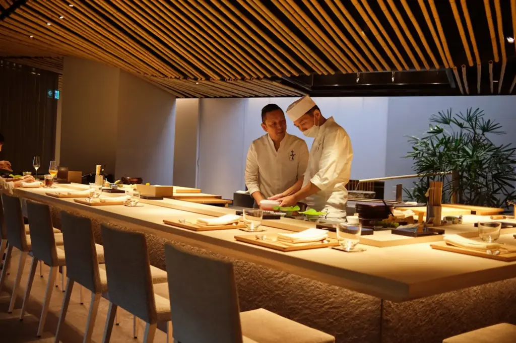 Chef Suzuki preparing an intimate, personalized Sushi Omakase experience in a refined Singapore restaurant, highlighting the culinary art of expertly curated, seasonal ingredients served in a tranquil dining environment.
