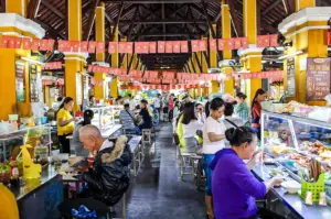 Interior of a Vietnamese food market with long counters, colorful banners, and diners enjoying local dishes.