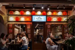 Cozy outdoor dining area at Niningashi Japanese Izakaya restaurant on East Coast, featuring patrons enjoying dinner under glowing red and white paper lanterns.