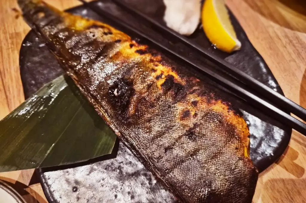 Moist Charcoal-grilled Hokke mackerel fish served with a lemon wedge and grated daikon radish at Niningashi Japanese Izakaya restaurant.