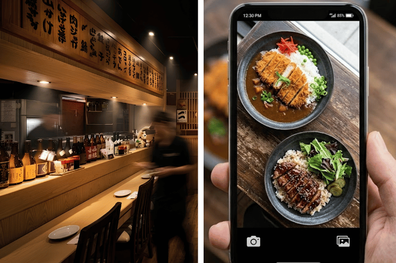 A split view showing a blurred staff member walking past a wooden restaurant counter lined with sake bottles and Japanese menu boards on the left, and a hand holding a smartphone photographing bowls of katsu curry and a sliced meat rice dish on the right.