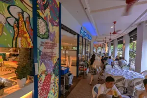 The entrance to Long Beach Seafood restaurant in Singapore, featuring vibrant wall art celebrating their award-winning original black pepper crab of the year, with outdoor dining tables visible.