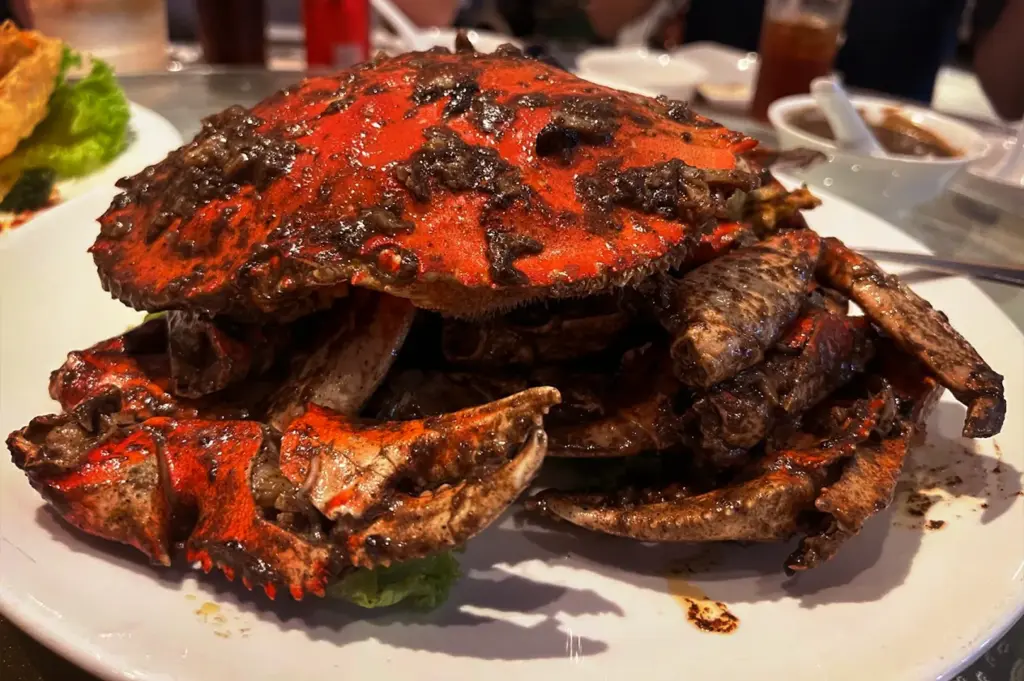 A close-up view of a whole, freshly cooked black pepper crab, a signature specialty dish served at Long Beach Seafood restaurant.