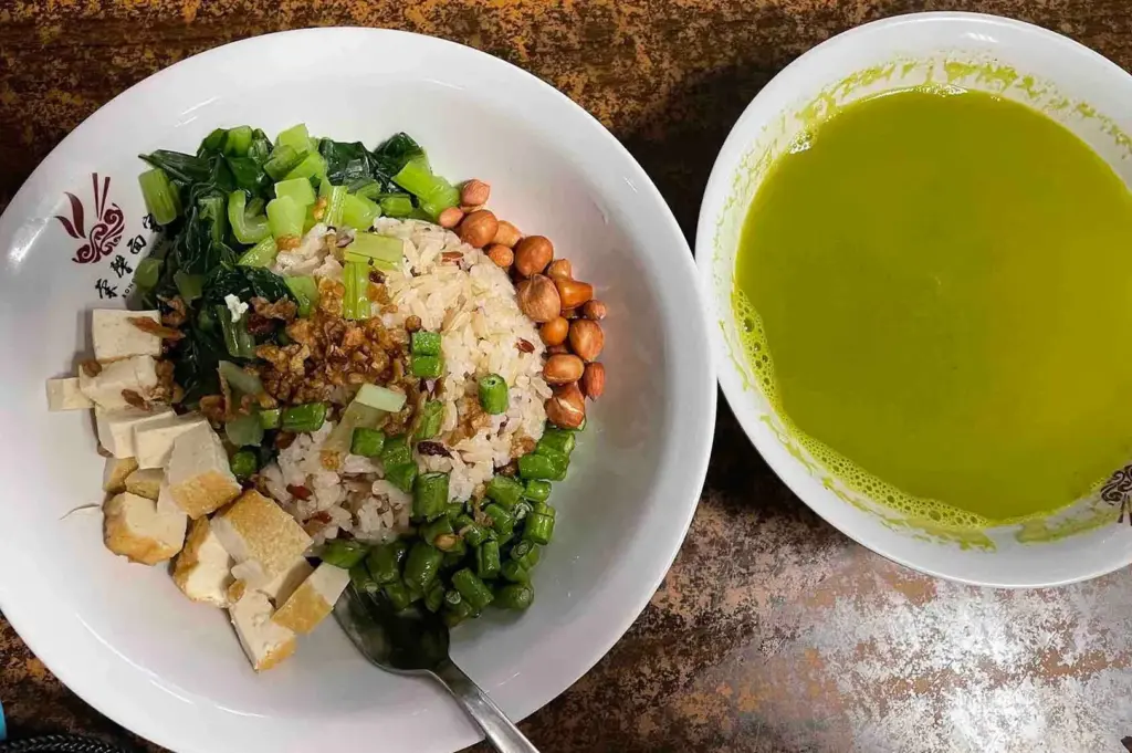The signature Thunder tea rice at New Green Pasture Cafe, featuring a nutritious brown rice set with tofu, green vegetables, and a side of warm herbal soup.