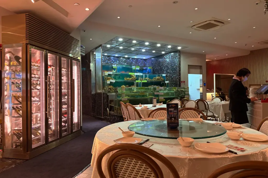 The interior of Long Beach Seafood restaurant, highlighting a large live seafood tank showcasing fresh crabs and fish, and a well-stocked wine refrigerator.