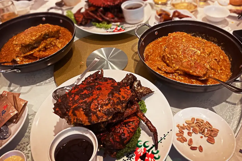A table spread at Long Beach Seafood featuring multiple signature crab dishes, including their famous black pepper and chili crab, ready to be enjoyed.