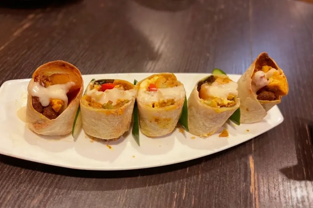 A plate of the Sri Lankan Rolls at New Green Pasture Cafe with vegetable fillings and creamy sauce.