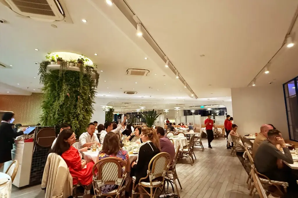 A vibrant, busy scene inside Long Beach Seafood restaurant with people enjoying meals near a large indoor vertical garden feature.