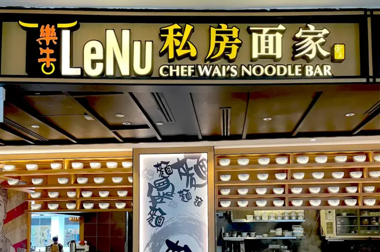 The modern, illuminated storefront signage of LeNu Chef Wai's Noodle Bar at VivoCity, featuring a decorative wall lined with ceramic bowls.