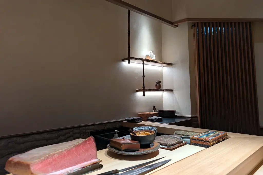 Minimalist Japanese interior featuring a clean wooden sushi counter at Sushi Zen Singapore, showcasing premium tuna cuts ready for an authentic Omakase experience.