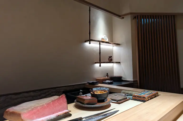 Minimalist Japanese interior featuring a clean wooden sushi counter at Sushi Zen Singapore, showcasing premium tuna cuts ready for an authentic Omakase experience.