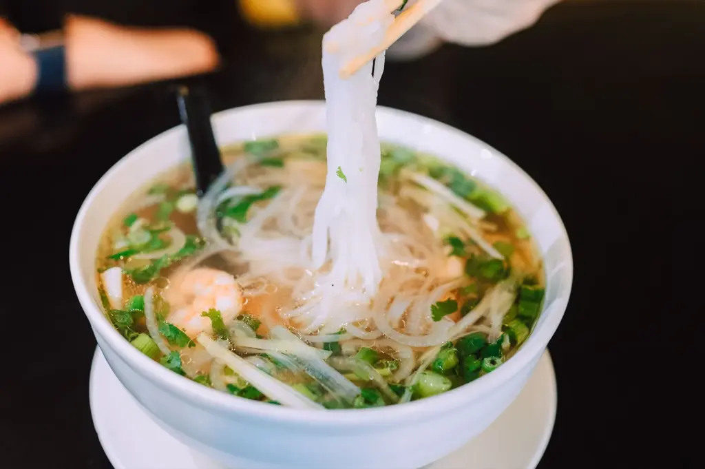 A steaming bowl of Chinese rice-based noodles in a flavorful broth with shrimp, representing the light and silky texture of the rice noodle family.