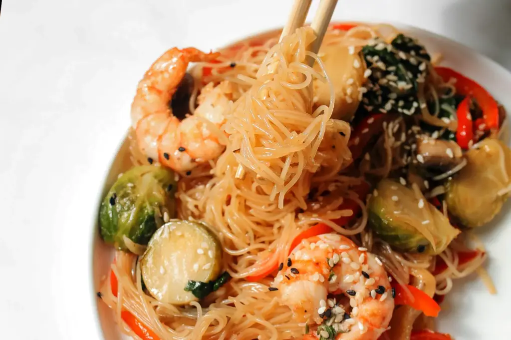 A delicious stir-fried dish featuring glass noodles, also known as vermicelli or starch-based noodles, mixed with shrimp and fresh vegetables