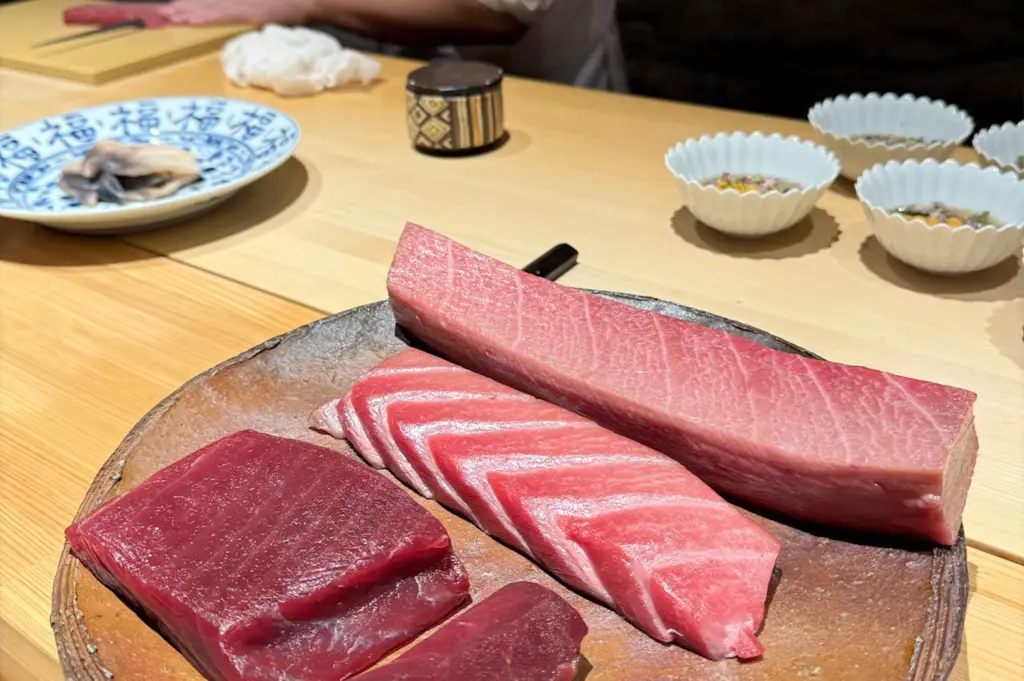 A premium selection of fresh tuna cuts, including lean akami and fatty otoro, presented on a ceramic plate at Sushi Zen Singapore, emphasizing the high-quality ingredients used in their Omakase.