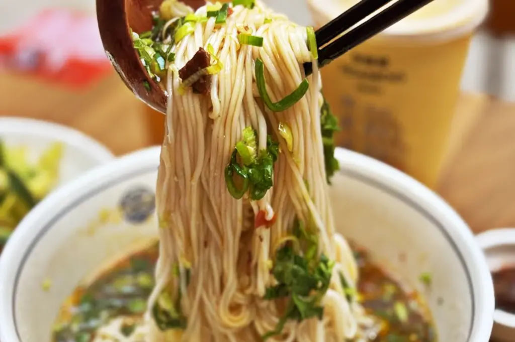 Springy hand-pulled noodles, the most essential ingredient, lifted with chopsticks from a rich, aromatic broth filled with green onions and tender meat slices.