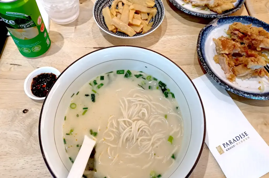 A top-down view of a complete meal at LeNu Chef Wai's Noodle Bar, including a creamy tonkotsu-style noodle soup, crispy fried chicken, and marinated bamboo shoots.