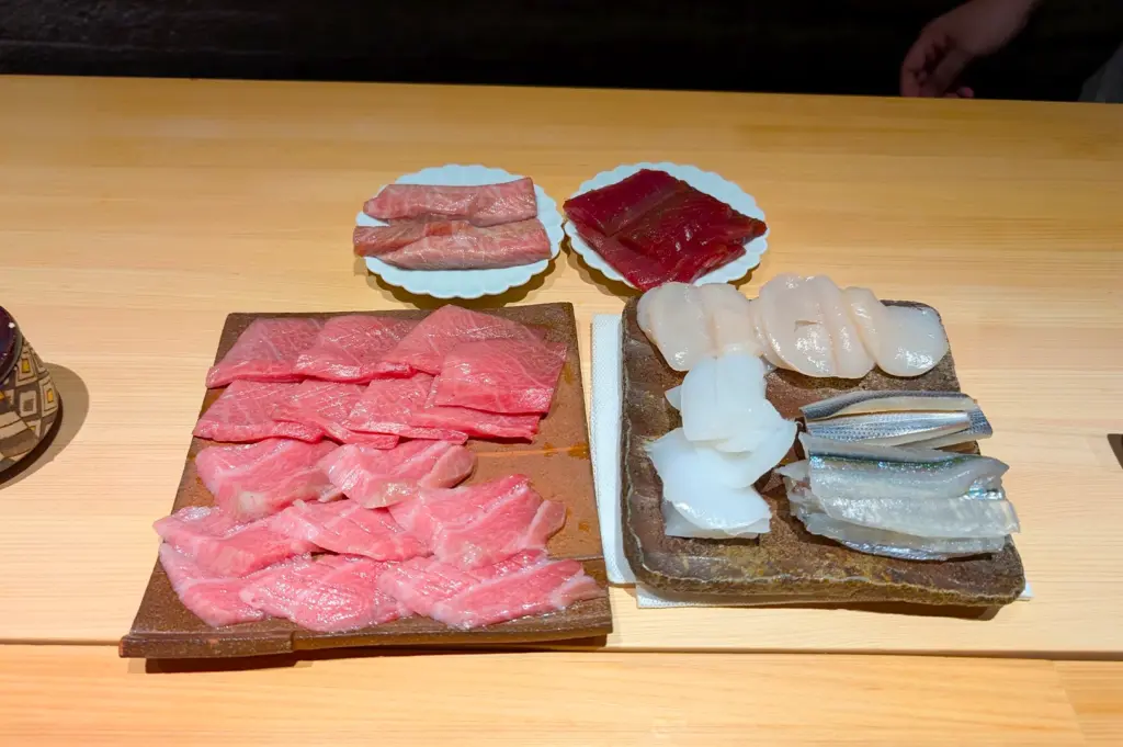 An array of premium sashimi, including fatty tuna, scallops, and squid, arranged on traditional stone platters at Sushi Zen Singapore, showcasing the artistry of their signature Omakase meal.