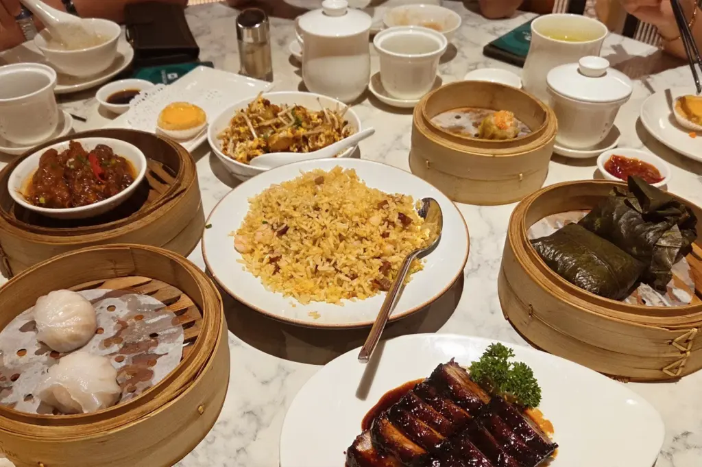 A decadent dim sum table spread at a Crystal Jade restaurant in Singapore, featuring signature pork ribs, fried rice, and freshly steamed har gow.