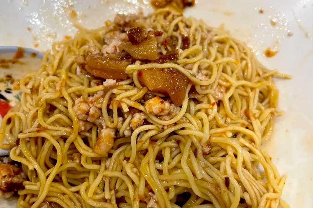 A serving of savory takeaway bak chor mee, a classic Singaporean dish featuring springy egg noodles tossed in a flavorful minced meat sauce.