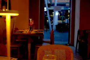 An intimate restaurant interior with warm, low lighting, cozy wooden tables, and a glowing table lamp, creating a slow-down atmosphere ideal for meaningful conversations.
