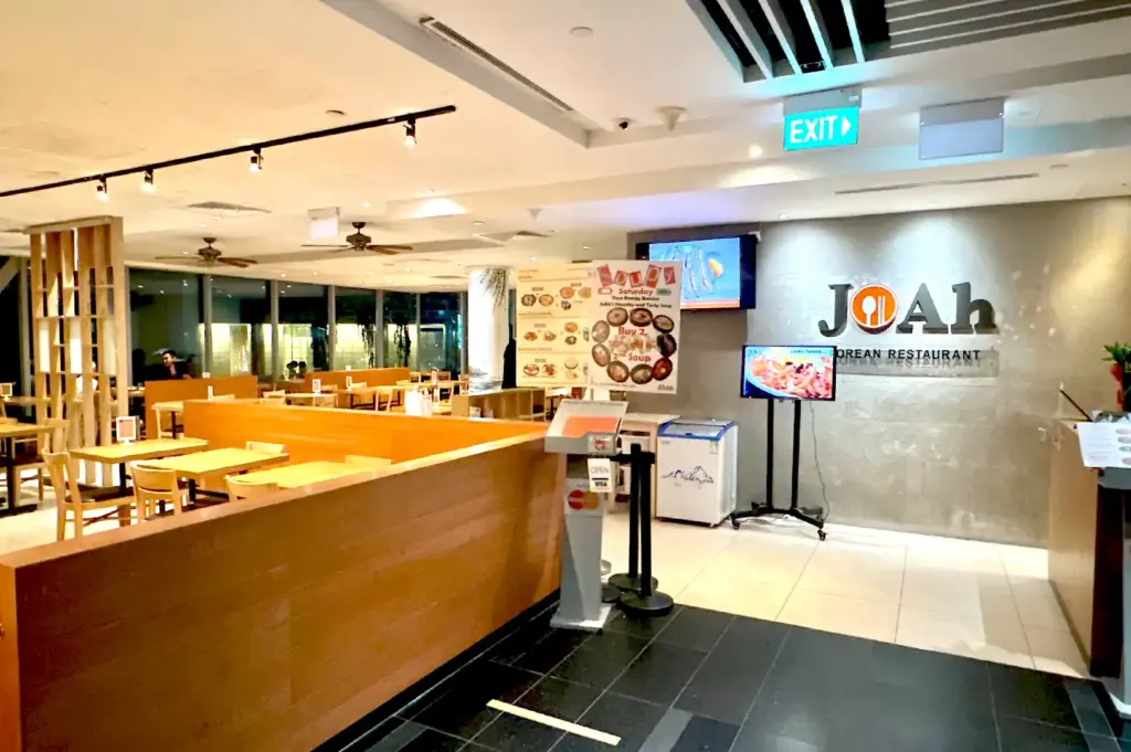 The warm, wood-paneled interior and entrance of JoAh Korean Restaurant, offering a spacious dining environment for office workers seeking lunch in the CBD.