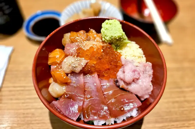A vibrant bowl of traditional Japanese Chirashi Don topped with assorted fresh sashimi, shiny ikura (salmon roe), and a dollop of wasabi.