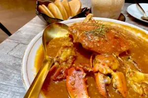 Classic chili crab smothered in thick, savory gravy served alongside golden-brown fried mantou bread at a vibrant Singapore seafood restaurant.